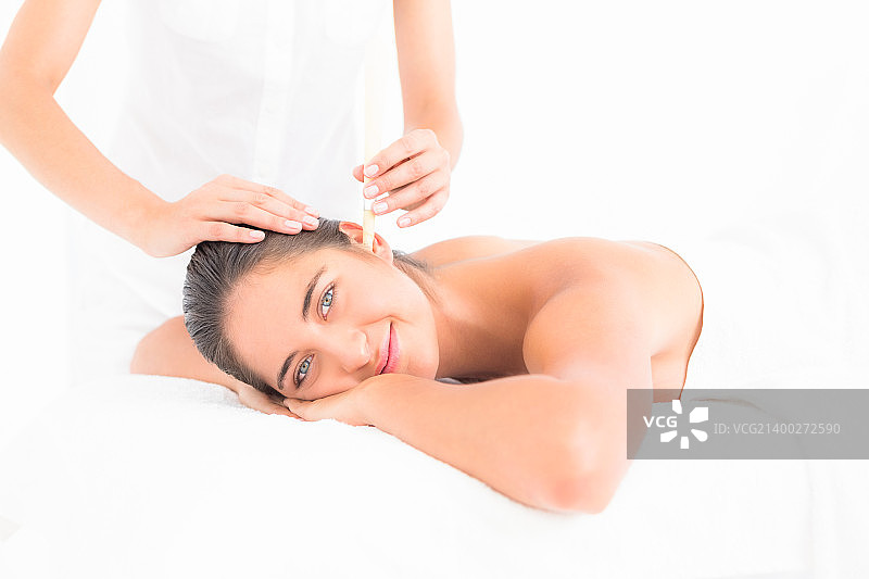 年轻女子在水疗中心接受耳烛护理的侧面照图片素材
