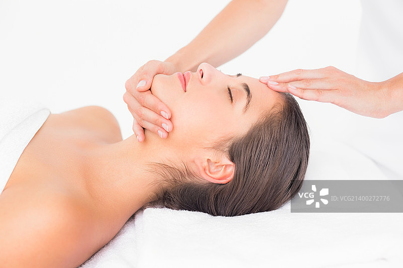 年轻女子在水疗中心接受头部按摩的侧视图图片素材
