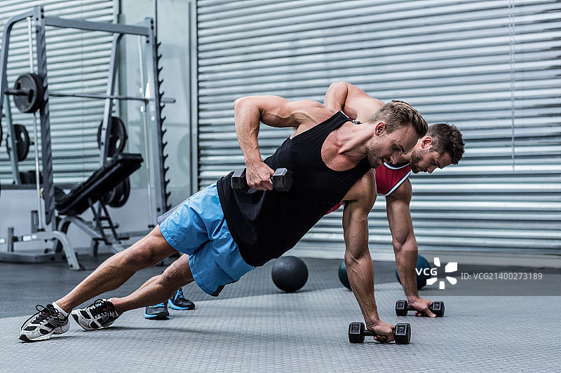 健壮的男人做侧平板支撑，举着哑铃图片素材