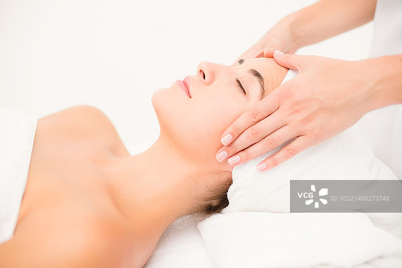 年轻女子在水疗中心接受面部按摩的特写图片素材