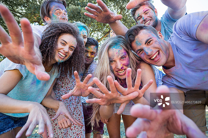 快乐的朋友在阳光明媚的日子里身上沾满彩色粉末图片素材