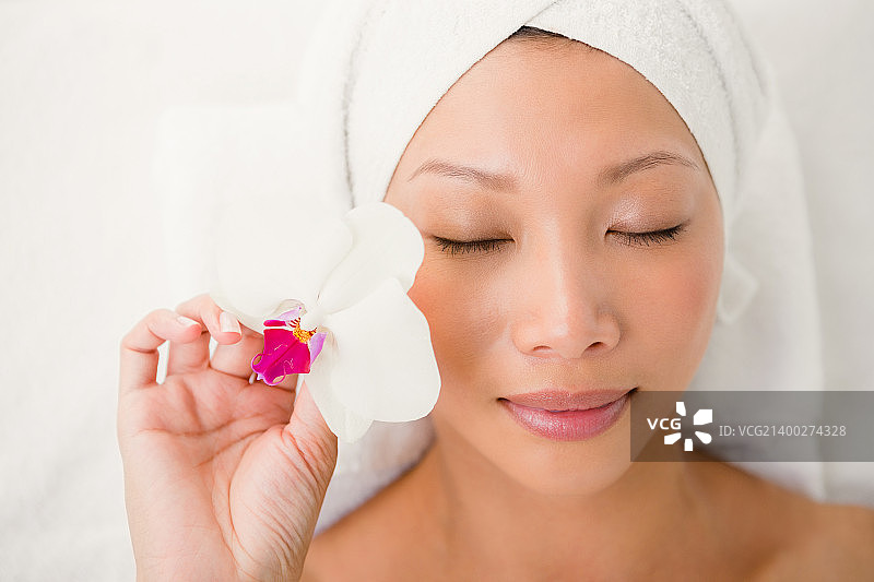 年轻女子在水疗中心拿着一朵花图片素材