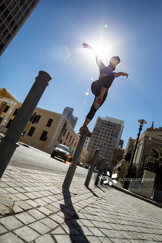 健壮的女人在城市中立柱上保持平衡图片素材