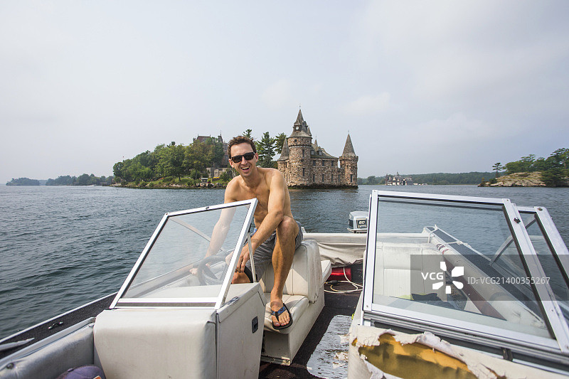 在纽约州北部千岛群圣劳伦斯河中驾驶旧船的男人图片素材