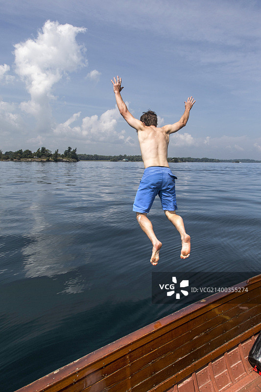 男人从圣劳伦斯河的古董木船上跳下图片素材