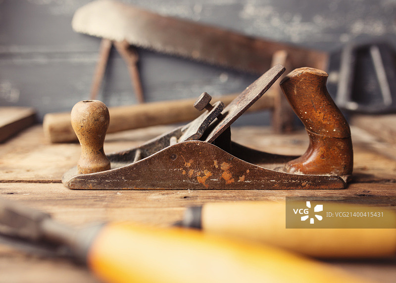 木制背景上的老式手工工具。焦点在手刨上。木匠工作场所。着色照片图片素材