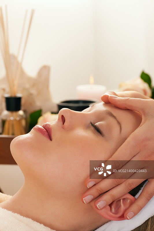 在水疗中心享受专业面部按摩的漂亮女人图片素材