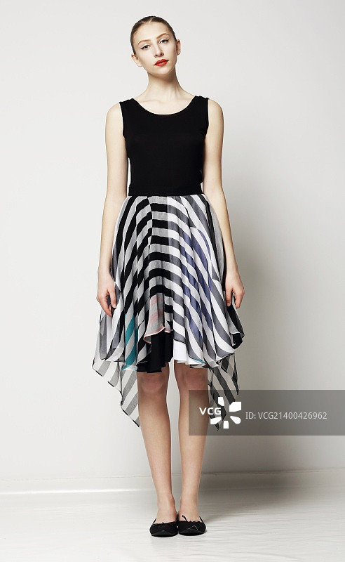 穿着条纹连衣裙的时髦女人全身像。春季工作日系列图片素材
