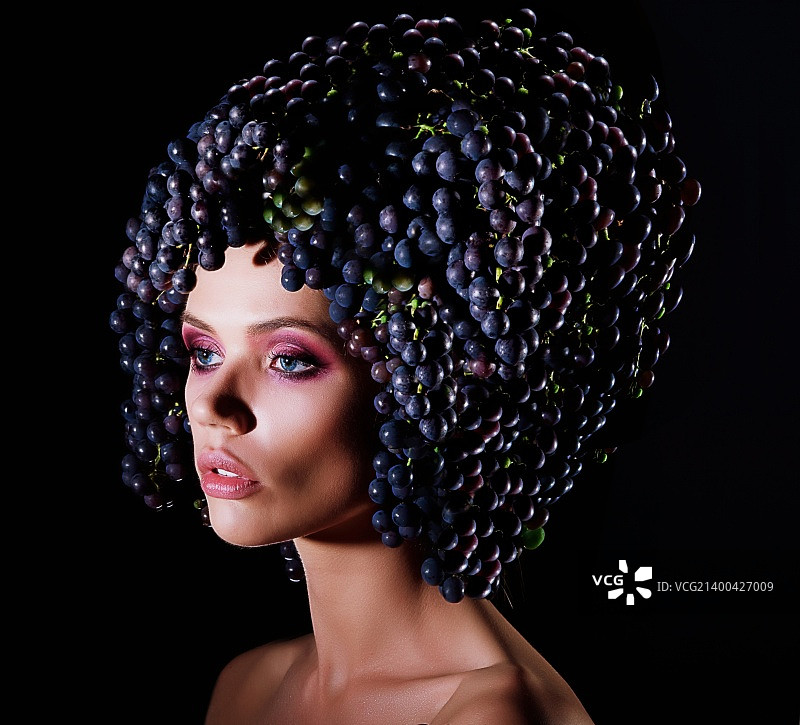 丰收节：手持蓝色葡萄藤的女子侧面轮廓图片素材