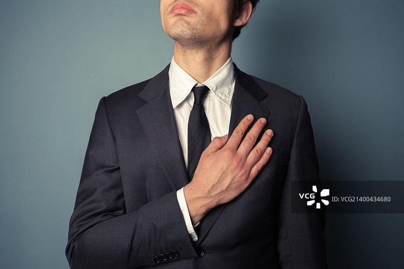 年轻商人宣誓效忠，手放在胸前图片素材