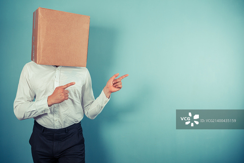 一位头上顶着纸箱的男士正在指点图片素材