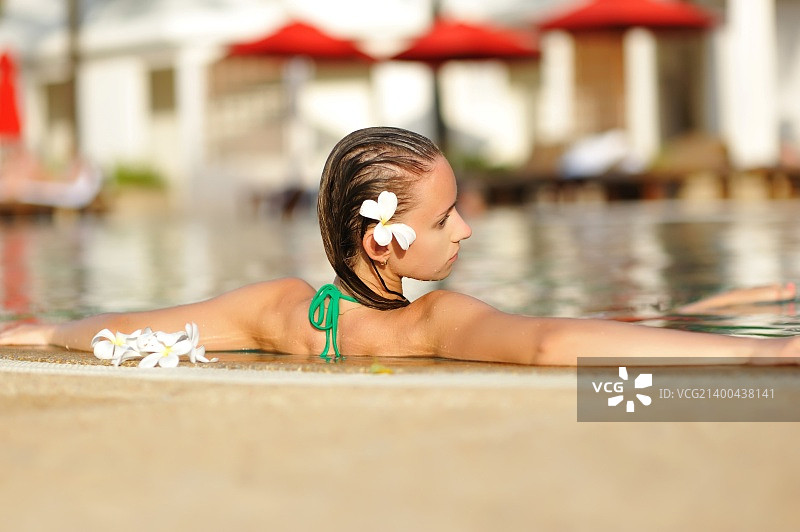 戴着鲜花的女孩在热带游泳池图片素材