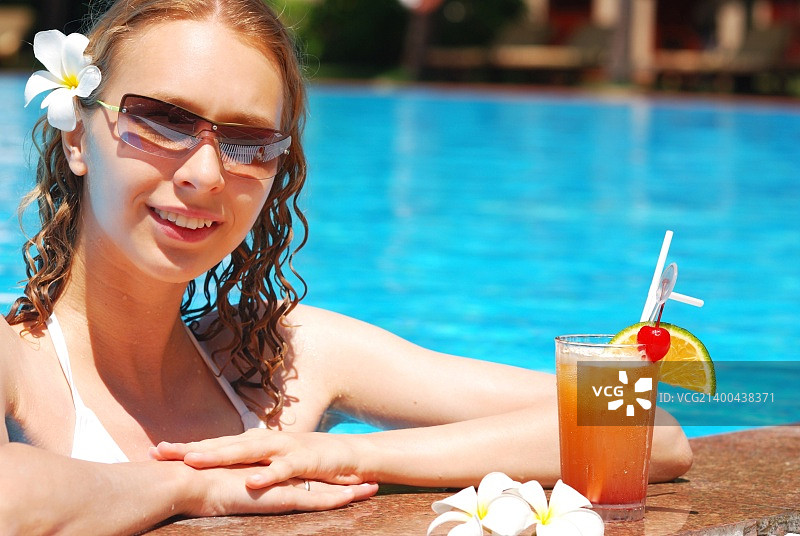 在热带泳池里喝鸡尾酒的女孩图片素材