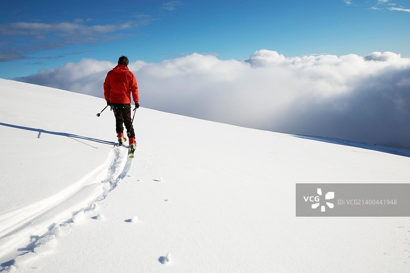 滑雪坡上的年轻男滑雪者；背面图图片素材