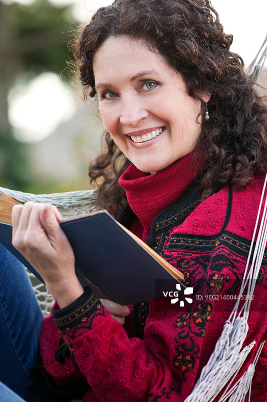 坐在吊床上看书的中年妇女图片素材