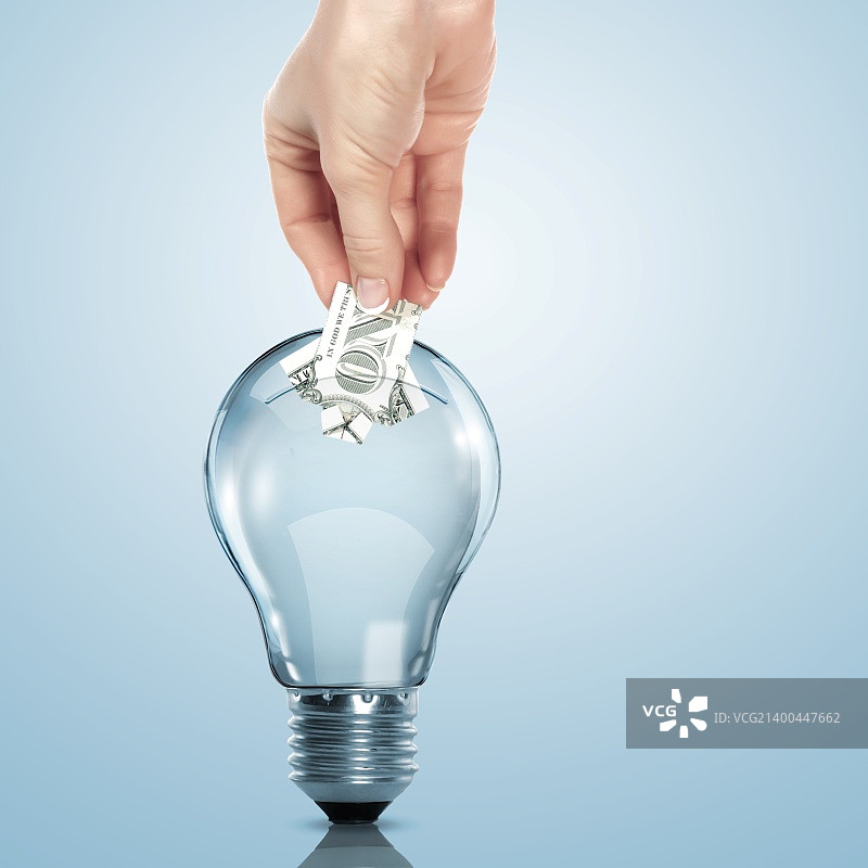 手和灯泡里的钱图片素材