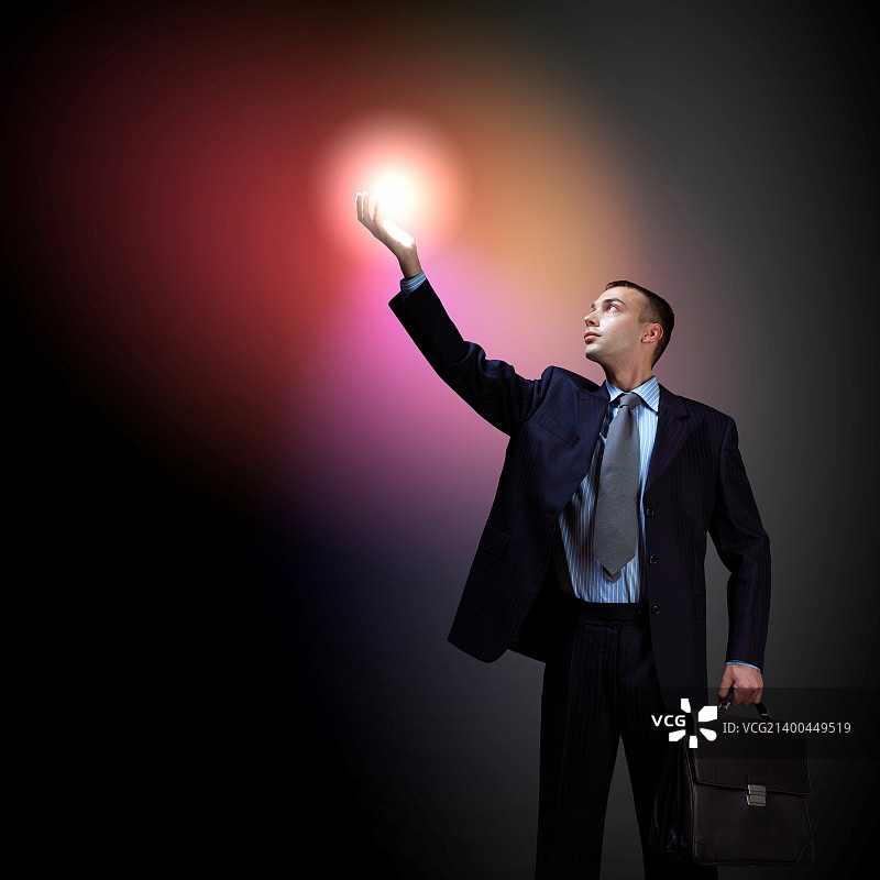 手持闪光的年轻有为的商人，象征着成功和进步图片素材