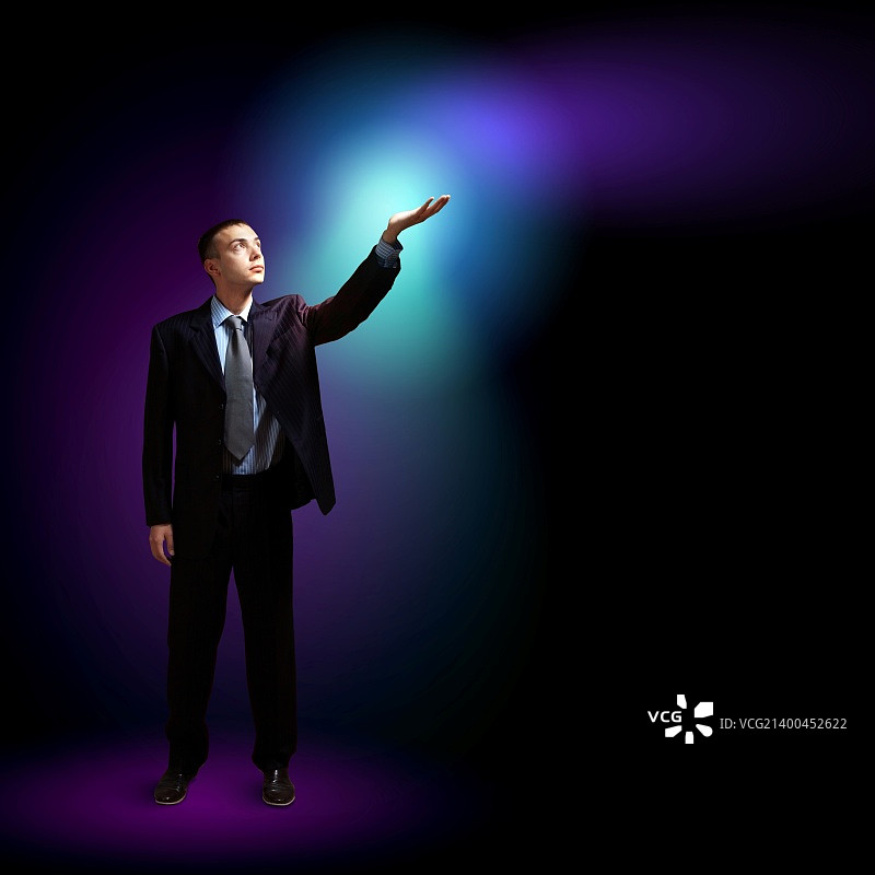 手持闪光的年轻有为的商人，象征着成功和进步图片素材