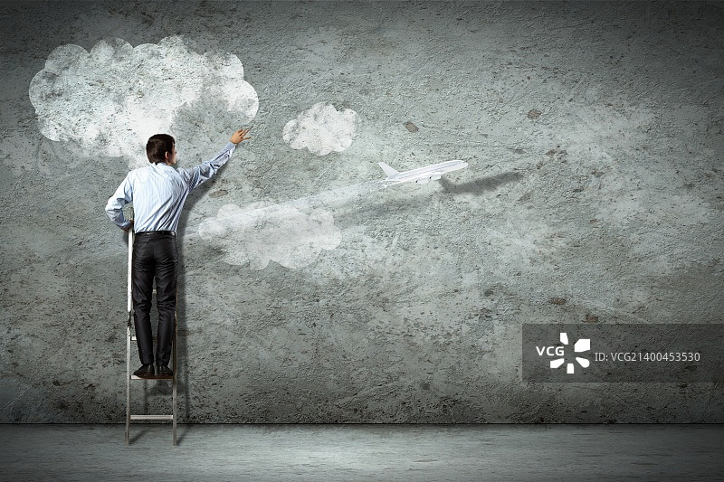 站在梯子上指着墙上图片的商人图片素材