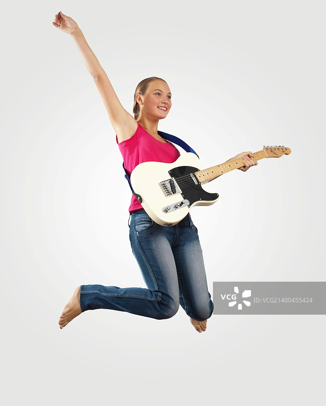 年轻女人弹电吉他跳跃图片素材
