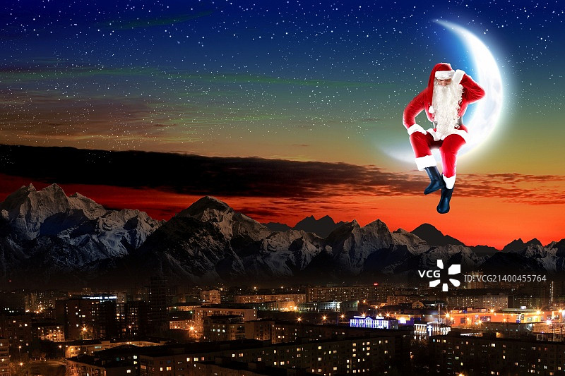 圣诞老人坐在月亮上，下方是城市和山脉的照片图片素材