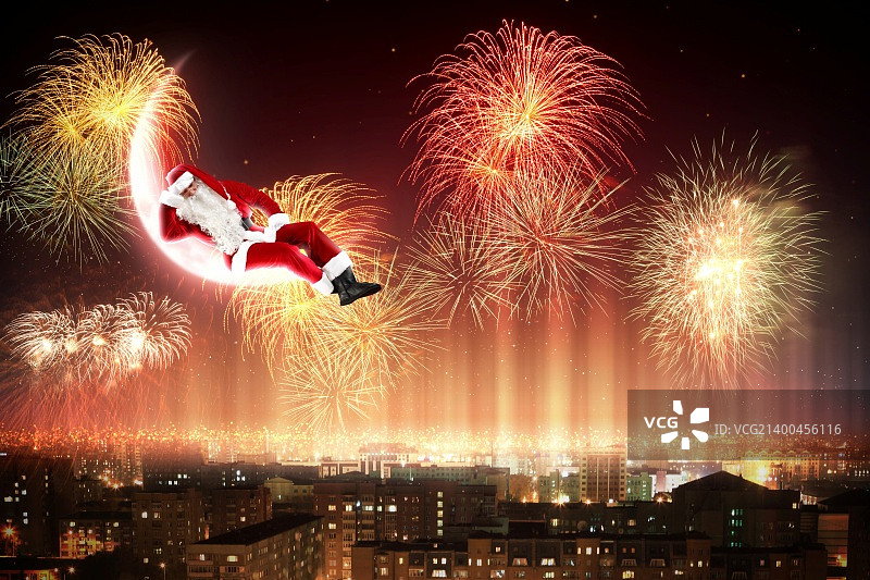 夜晚城市上空月亮上的圣诞老人图片素材