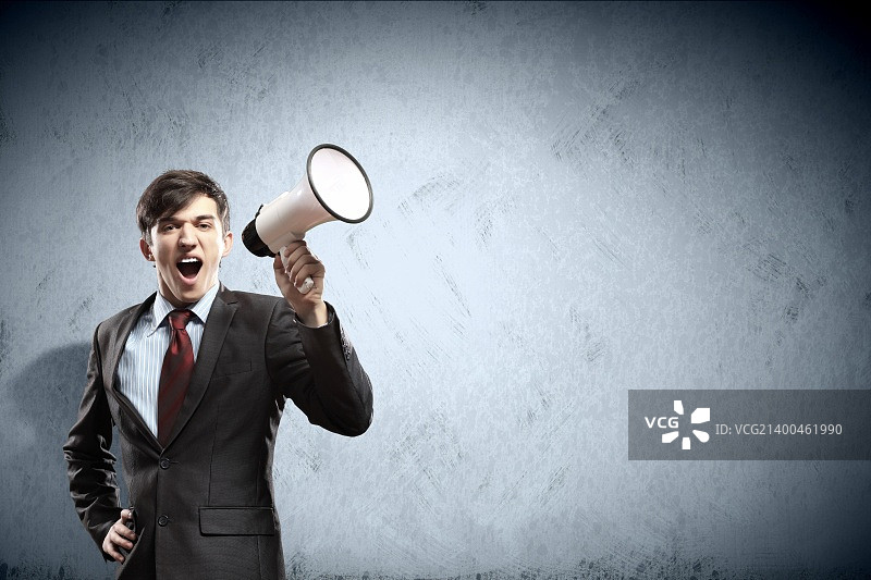 身穿黑色西装的年轻商人对着扩音器尖叫图片素材