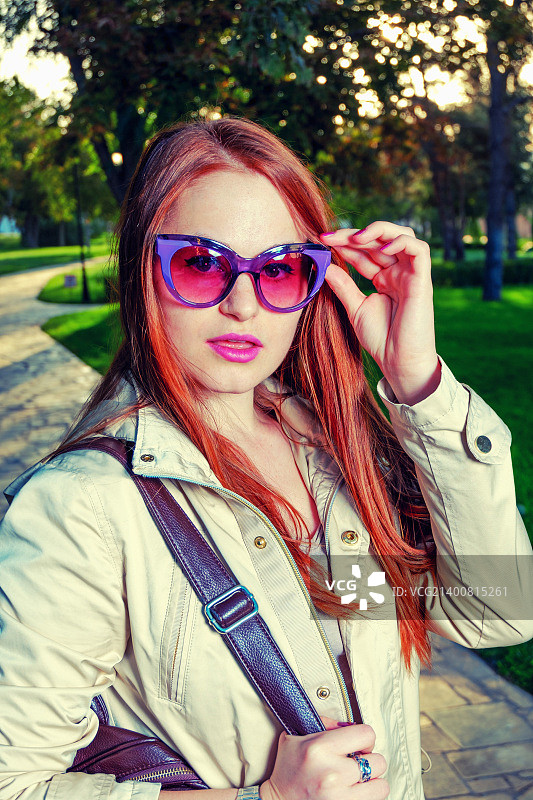 站在公园巷子里的时尚红发女孩。都市时尚概念，红唇...图片素材