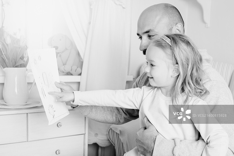 可爱的金发女孩给父亲送画，父亲节概念图片素材