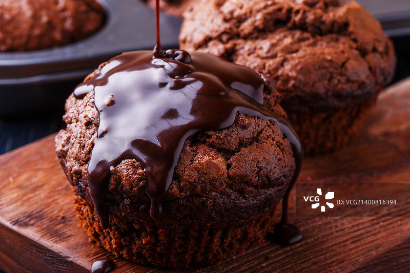 深色背景上的巧克力麦芬与巧克力糖浆图片素材