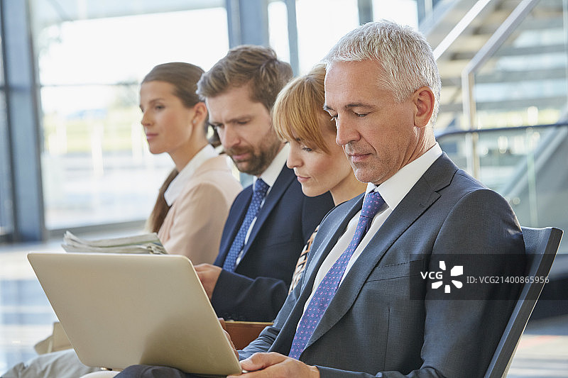 商务男人在机场出发区使用笔记本电脑工作图片素材