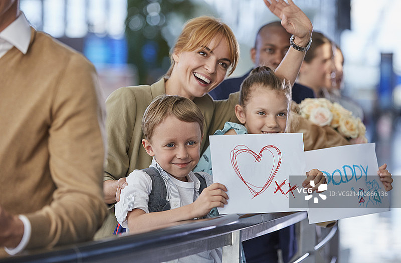 母亲和孩子们在机场拿着欢迎标志迎接父亲图片素材
