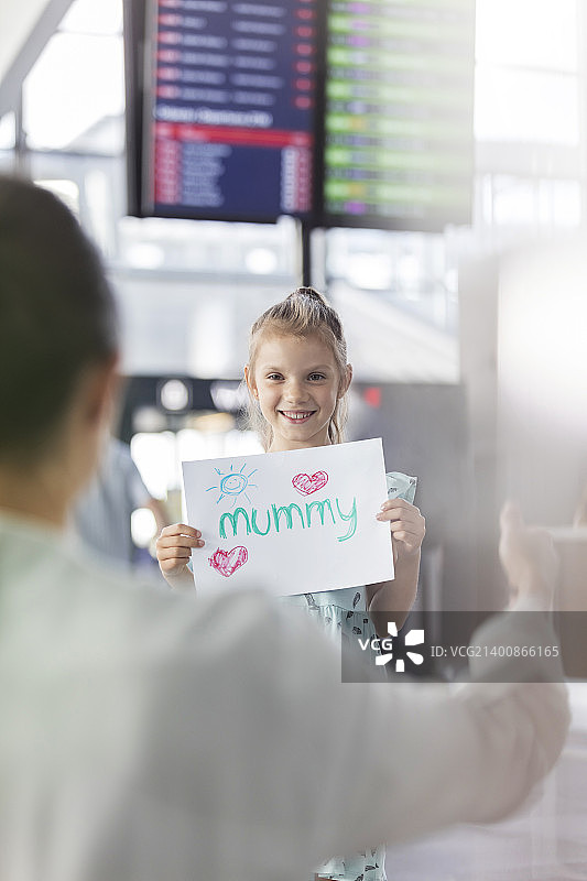 女儿在机场举着欢迎牌迎接母亲图片素材