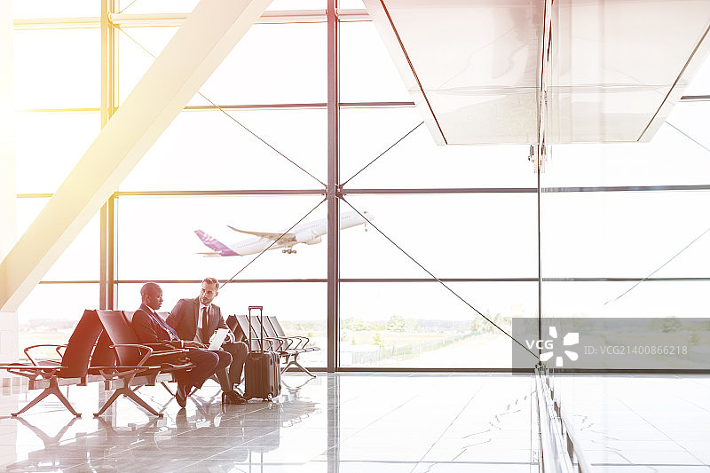 商人在机场候机区用笔记本电脑交谈工作图片素材