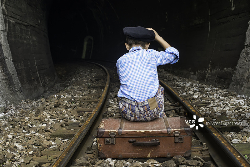 穿复古服装的孩子坐在铁轨上图片素材
