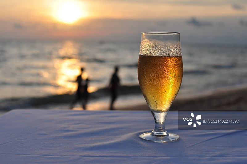 日落海滩上的一杯冰镇啤酒图片素材