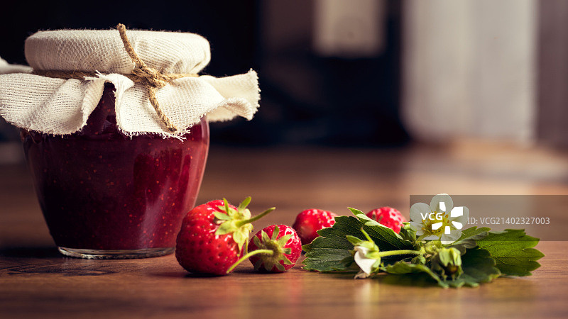 木质背景罐子里的自制草莓果酱图片素材