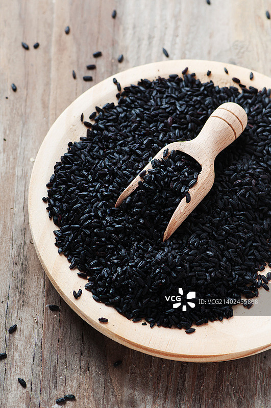 木桌上的黑色未煮熟的米饭图片素材