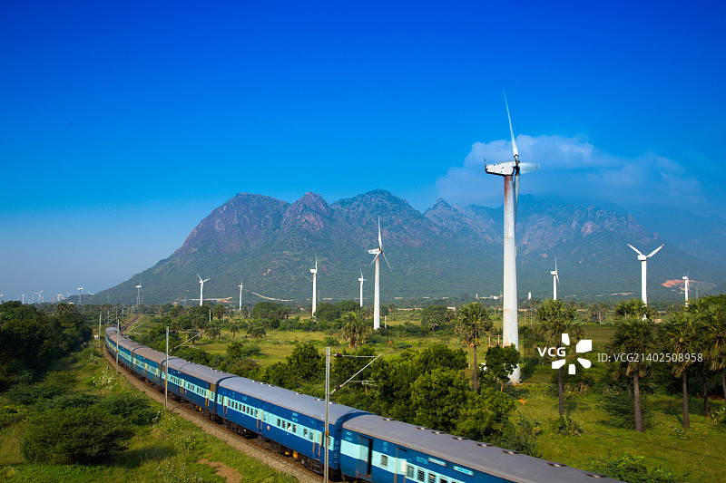 山脉和风力涡轮机背景下的印度火车图片素材