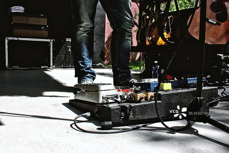 穿紧身牛仔裤和效果器踏板的吉他手图片素材