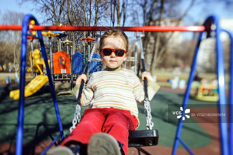 可爱的小女孩在儿童游乐场荡跷跷板图片素材