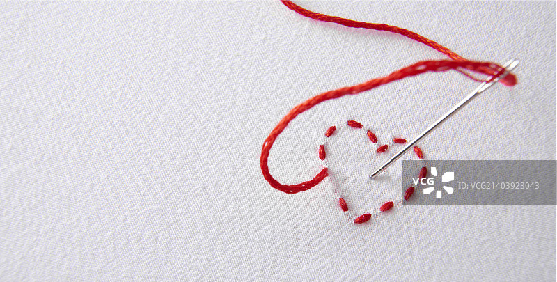 白色布上刺绣的红色爱心，带针孔图片素材