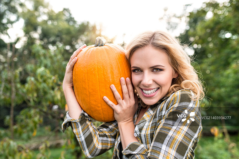 在花园里采摘南瓜的漂亮年轻金发女子图片素材