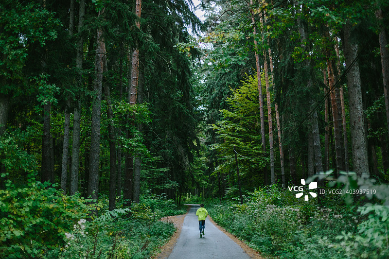 男人在古老绿色森林的小路上奔跑图片素材