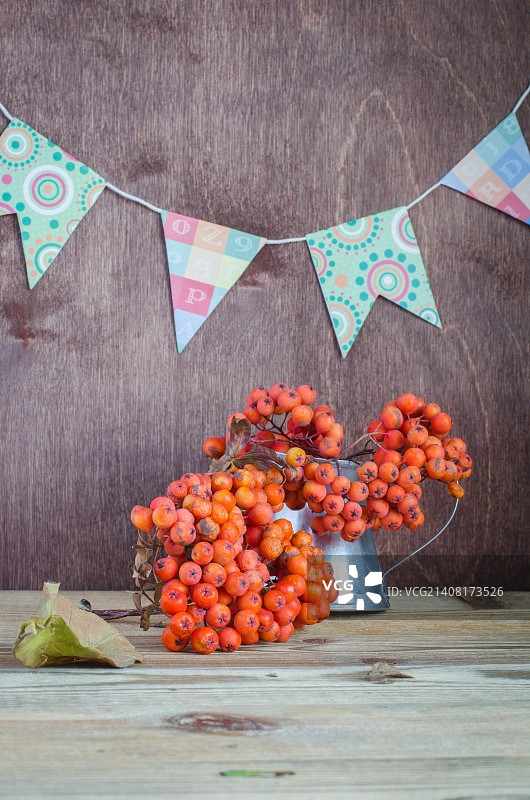 花楸果穗在罐子中，背景是旗帜花环的秋季静物图片素材