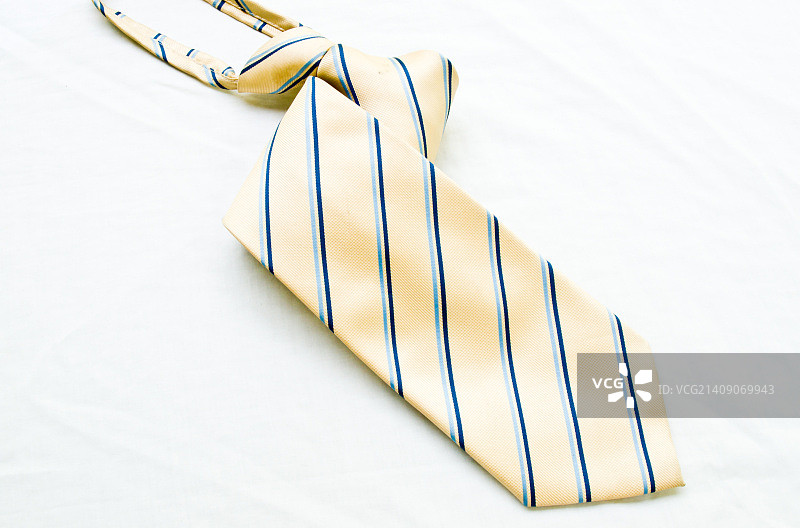 一条卷起来的黄蓝相间的条纹领带，隔离在白色背景上图片素材