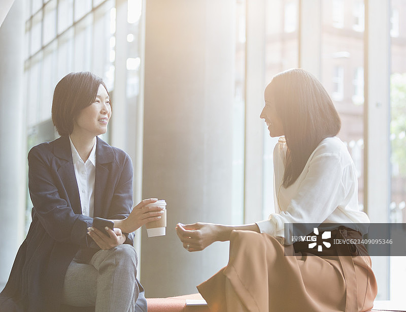 女商人们在阳光明媚的大厅里享受着喝咖啡的休息时间图片素材