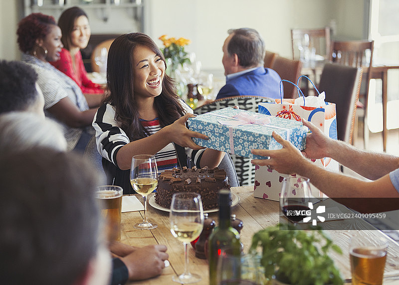 在餐馆餐桌旁收到朋友生日礼物的微笑女人图片素材
