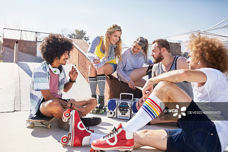 在阳光明媚的滑板公园里，穿着旱冰鞋听音乐的朋友们图片素材