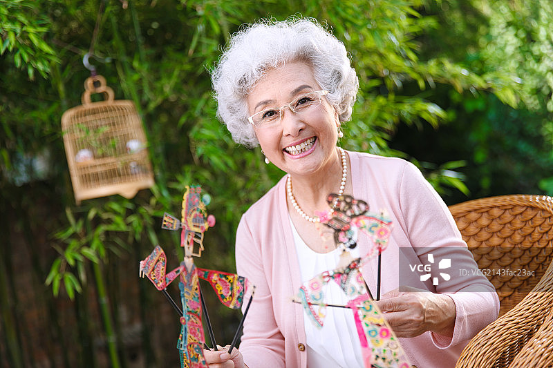 一个老年女人拿着皮影偶图片素材